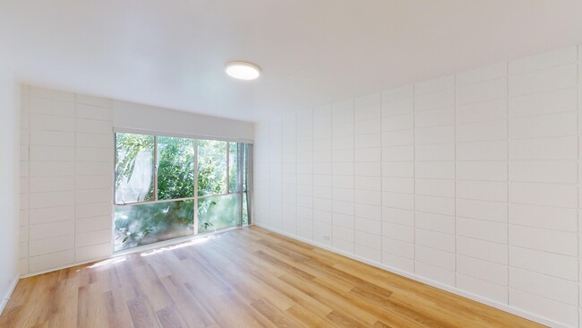 Spacious room with wood-like flooring and a large window offering natural light - 2627 Hillegass Avenue