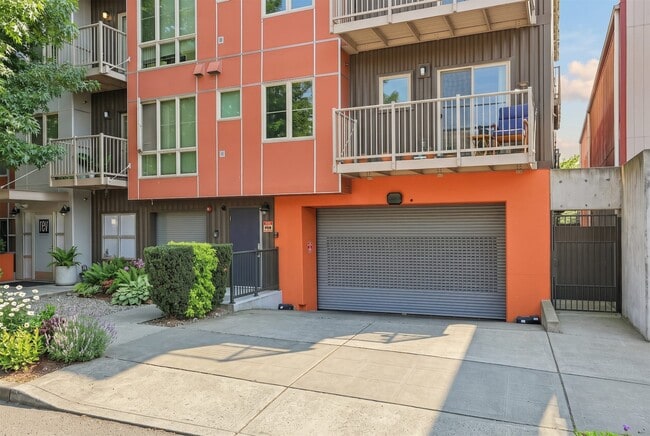 Exterior view of REV Fremont in Seattle featuring modern siding, private balconies, and secure garage parking access. - REV Fremont