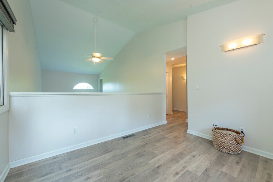 Expansive second-level landing showcasing contemporary plank flooring and dramatic vaulted ceiling. - 405 Windswept Dr
