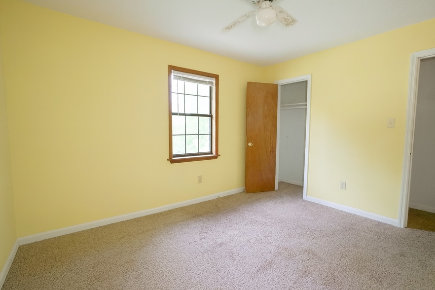 Bright guest bedroom with soft light, neutral carpet, and cheerful yellow walls. - 2313 Salem West Dr