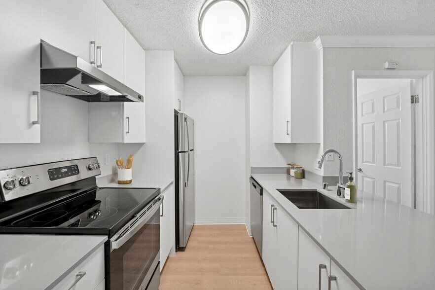 Renovated Package I kitchen with white cabinetry, grey quartz countertops, and hard surface flooring - eaves West Valley