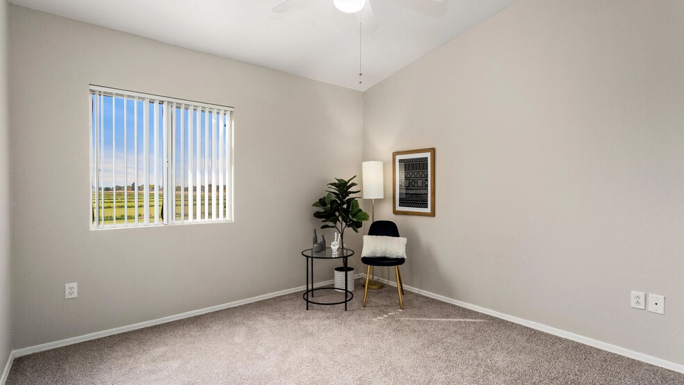 Bedroom featuring soft, neutral carpeting, multi-speed ceiling fan, and a sunlit window. - Riverwood Apartments