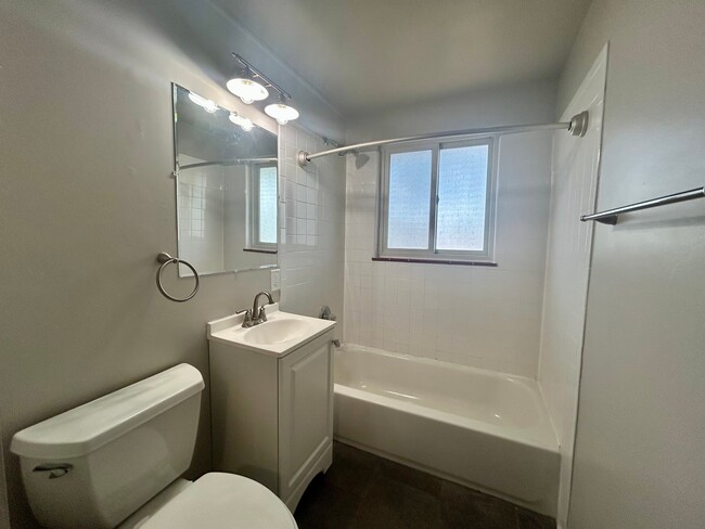 Bright bathroom with modern fixtures, featuring a bathtub, vanity, and a large mirror under natural light. - Boardwalk Apartments