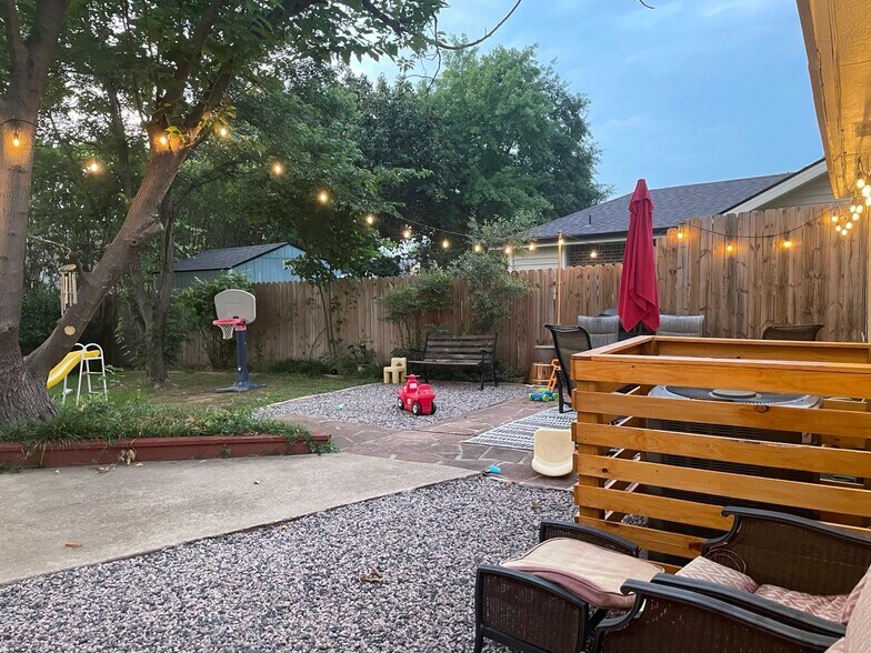 Peaceful fenced yard with ambient lighting, shade, and room to unwind. - 2401 Thistle Ct