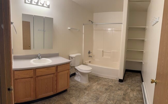 Well-lit bathroom with a full tub/shower combo, extended vanity, and built-in shelving. - 2979 Badger Rd