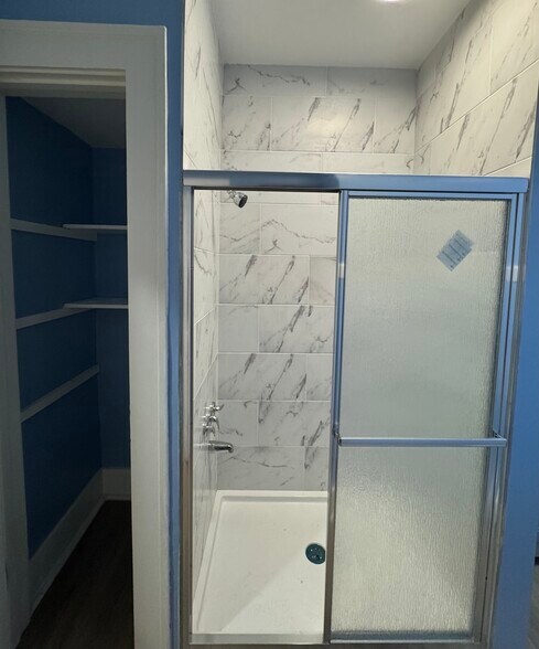 Tiled walk-in shower with sliding glass doors and built-in shelving. - 898-902 Portland Ave