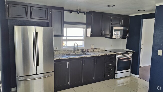 Kitchen with stainless steel refrigerator, electric stove, and microwave. - 7905 Harwell St