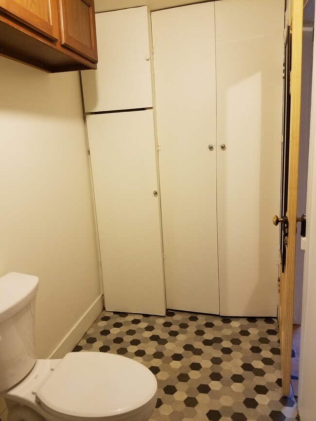 Bathroom, west wall. Cabinets at doorway. - 15 Goodrich St