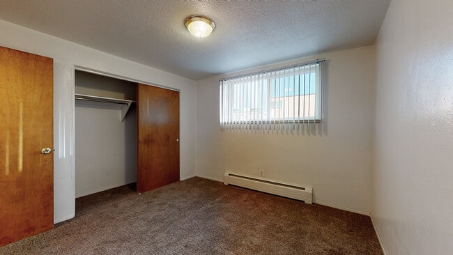 Experience comfort in this spacious bedroom with ample natural light. - Melody Apartments