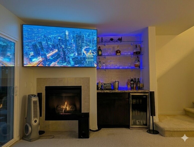 Living room TV, fireplace, bar, mini-fridge, and hidden entertainment center. - 3542 Shoreline Bluff Lane