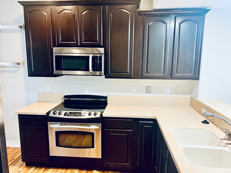 Kitchen with electric stovetop and to the left is a rack to hang pots & pans for more storage. - 2317 Decatur St
