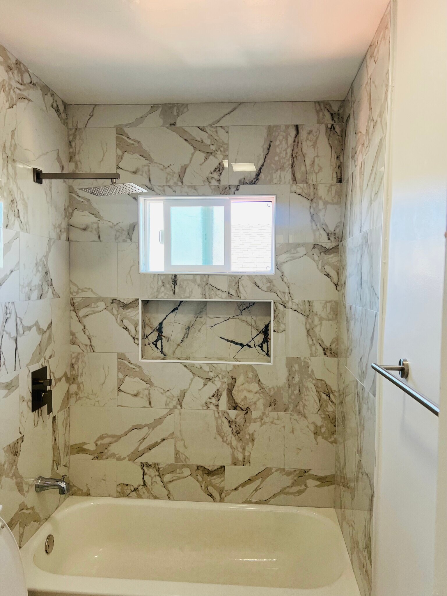 Newly remodeled bathroom featuring a rain shower head, modern finishes, and a framed vanity mirror - 3551 W Manchester Blvd
