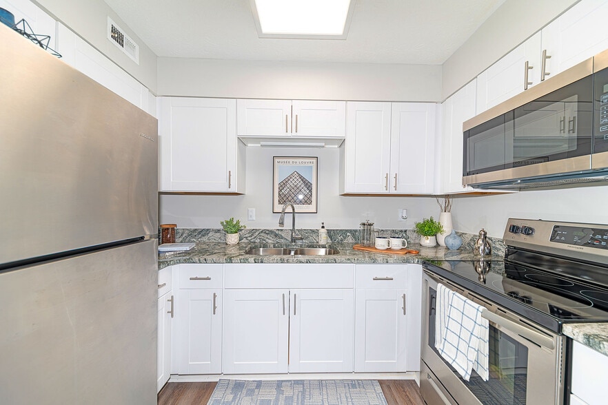 Kitchen with granite counters, stainless appliances, and modern cabinetry - The August