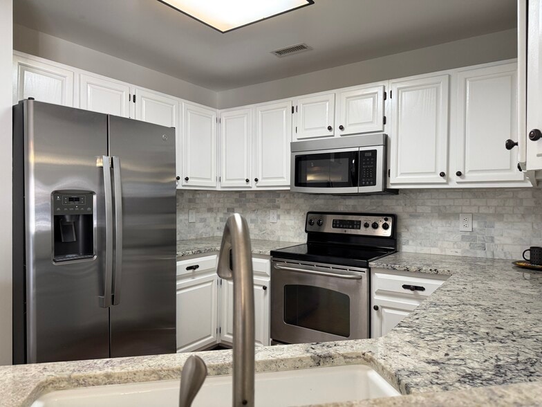 Kitchen w/ SS appliances, granite countertops, and tiled backslpash - 1133 Torrence Cir