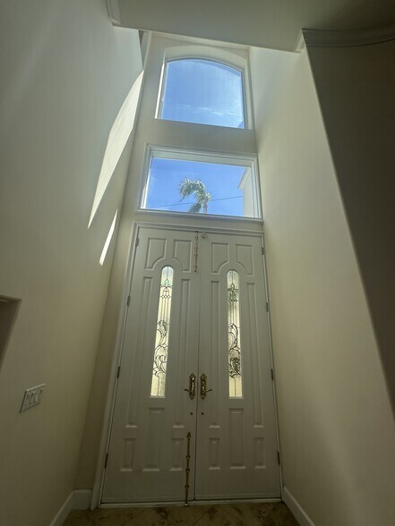 Grand double-door entry with decorative glass panels, soaring windows, and transom detail - 8120 Billowvista Dr