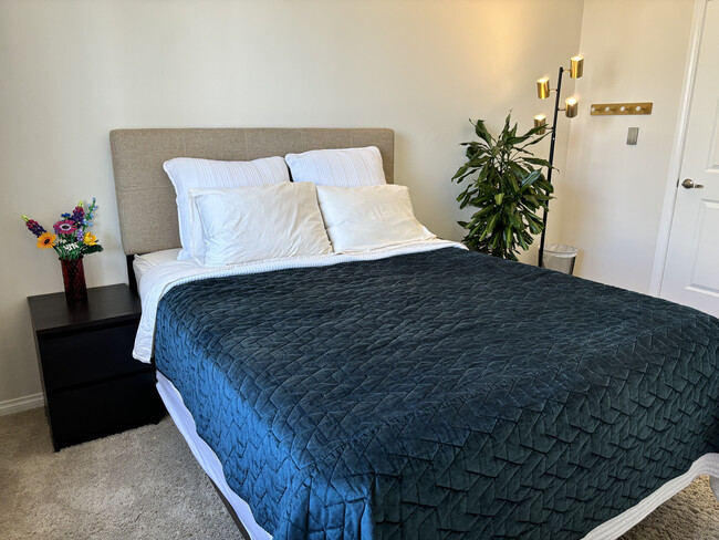 Serene bedroom setup with luxurious bedding, modern lighting, and touches of fresh greenery - 3740 Santa Rosalia Dr