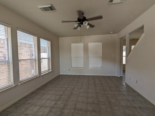 Large living room with ceiling fan and windows on ever wall. - 5910 Hollister Cole