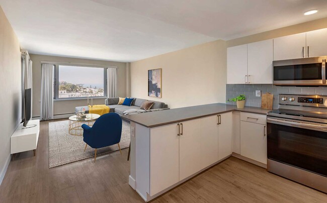 Limited availability: newly renovated Finish Package II apartment homes featuring kitchens with grey quartz countertops, white cabinetry, stainless steel appliances, grey tile backsplash, and hard surface flooring - Avalon Sunset Towers