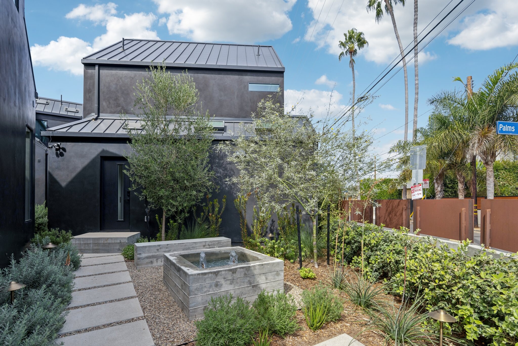 Secondary entrance courtyard with seating area and water feature. - 1169 Palms Blvd