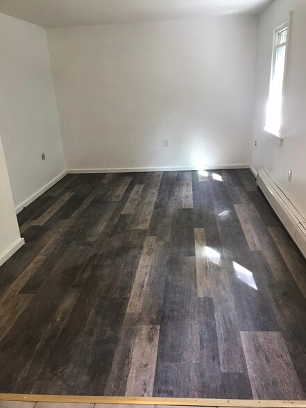 Newly installed flooring within living room portion of open space. - 122 Dewey avenue