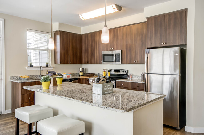 Two bedroom open concept kitchen with granite countertops, stainless-steel appliances, kitchen island and hard surface flooring - Avalon Laurel