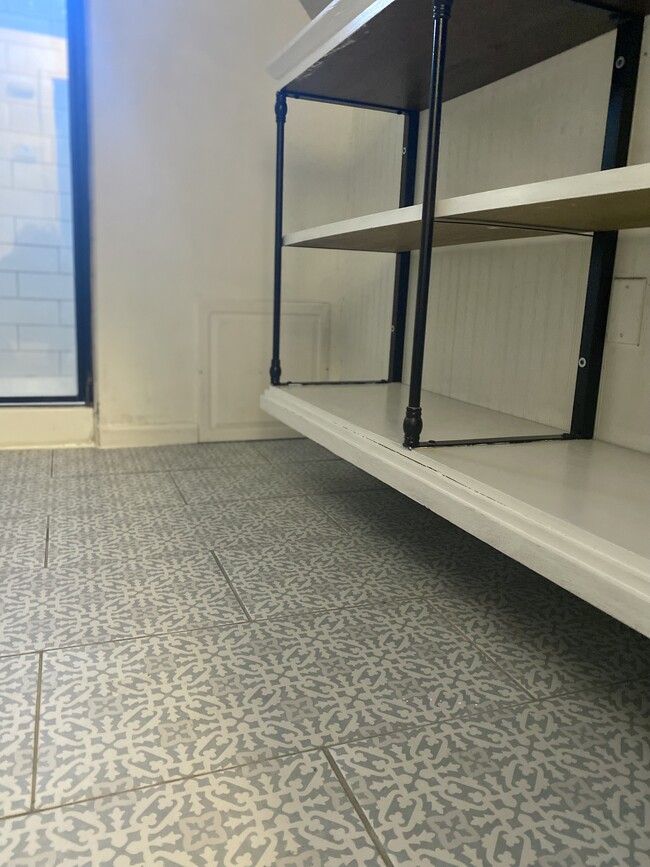 Bathroom with ceramic tile floor with open shelving. - 16 Eames St