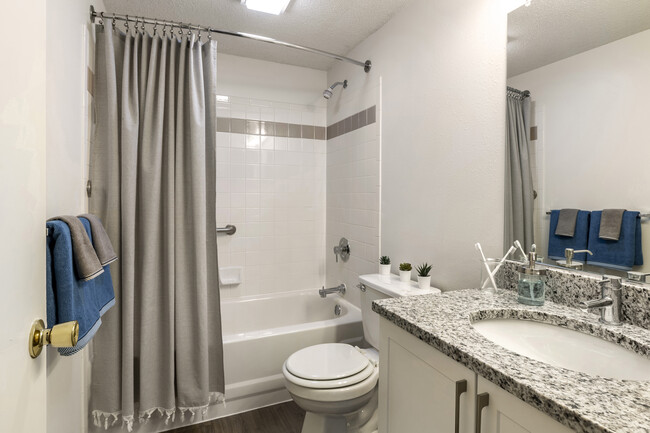 Renovated Package III bath with white cabinetry, grey granite countertops, and shower and bath with tile backsplash - eaves Washingtonian Center