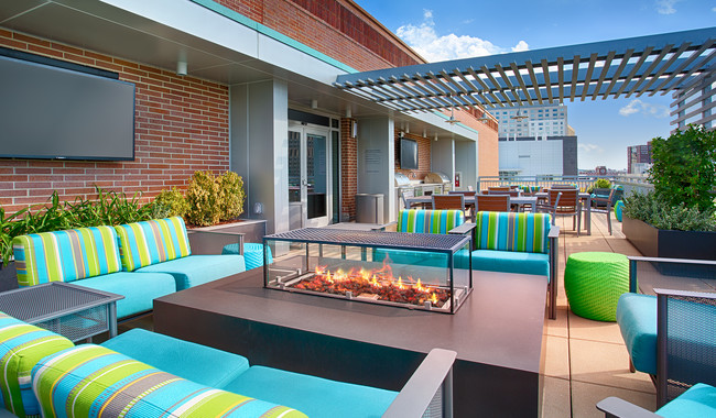 Hang out on the rooftop social deck with grilling stations, wall-mounted TVs, dining space, and views - Vivo Apartments