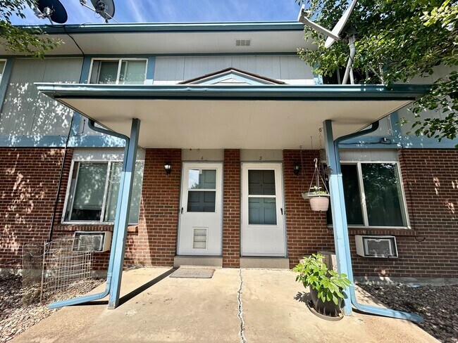 Charming townhouse entrance with a brick facade, elegant blue trim, and inviting porch area. - 10756 West 12th Lane