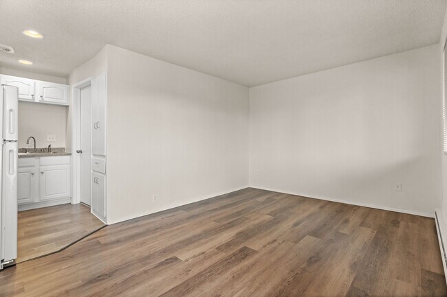 Spacious living area with modern wood-style flooring and a clean, neutral layout ready for your personal touch. - Highland Court Apartments