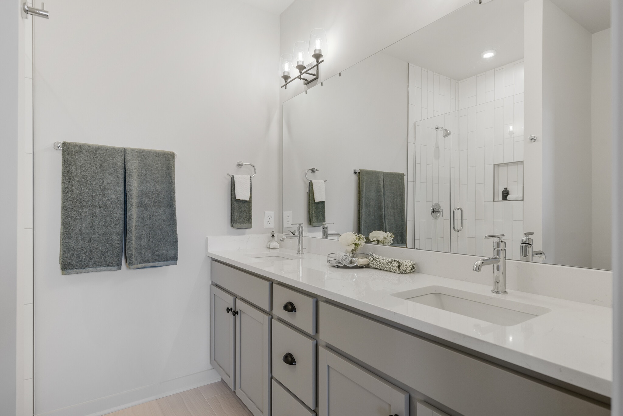 Spa-inspired en-suite featuring dual vanities, quartz countertops, and a frameless glass shower. - 358 E Village Ln
