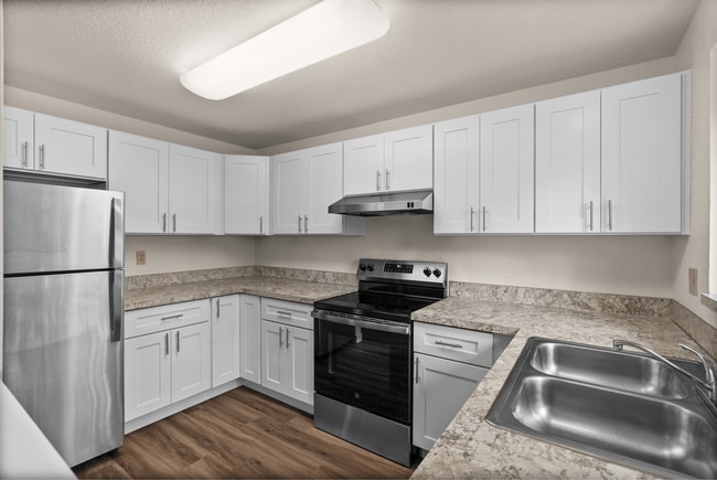 Cook in style with this updated kitchen featuring sleek stainless steel appliances, spacious white cabinetry, and elegant marble-look countertops. - Windemere Apartments