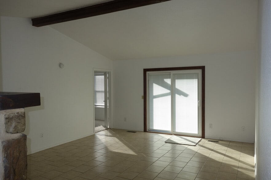 Vaulted and Beamed Living Room with sliding patio door to backyard. Primary bedroom door on left - 6604 S Utica Pl