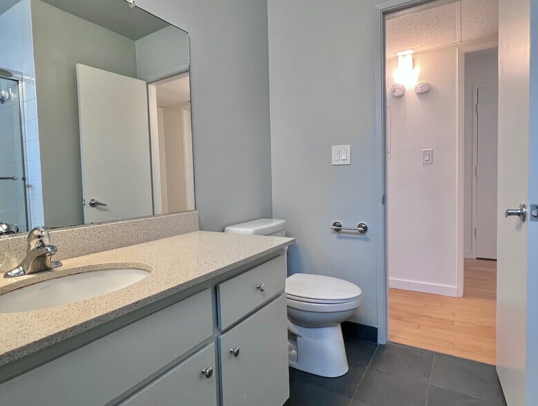 Updated bathroom with modern finishes, glass-enclosed tub/shower, and ample counter space. - 11639 Chenault St
