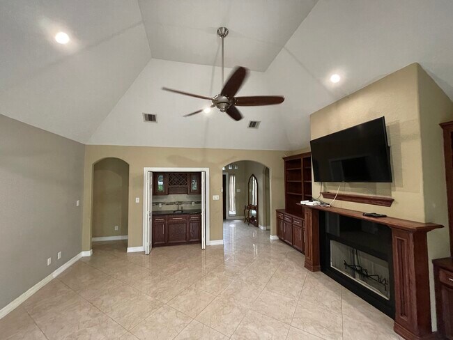 Living room with wet bar, high vaulted ceilings, recess lighting, custom wood cabinets, chimney - 600 River Bend Dr