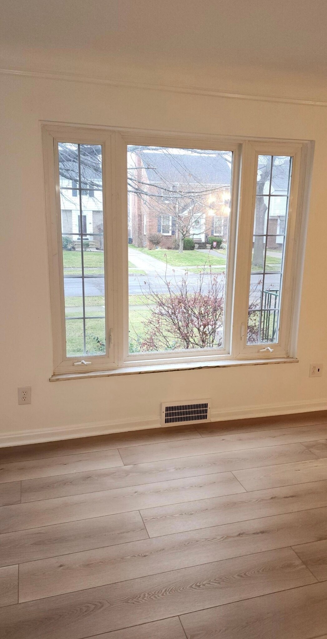 Sun-filled living area featuring a large picture window with side panels, offering abundant natural - 90 E 216th St
