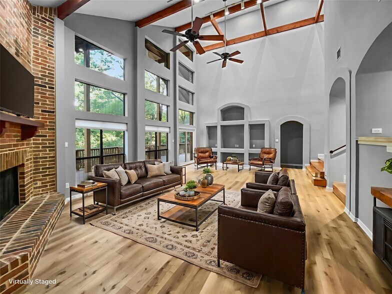 A stunning living room with a high vaulted ceiling, LVP flooring, a cozy gas brick fireplace, and a - 1314 Creekwood Dr