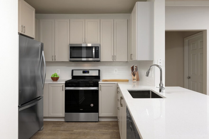 Renovated II kitchen with grey cabinetry, white quartz countertops, stainless steel appliances, white tile backsplash, and hard surface flooring - Avalon at Grosvenor Station