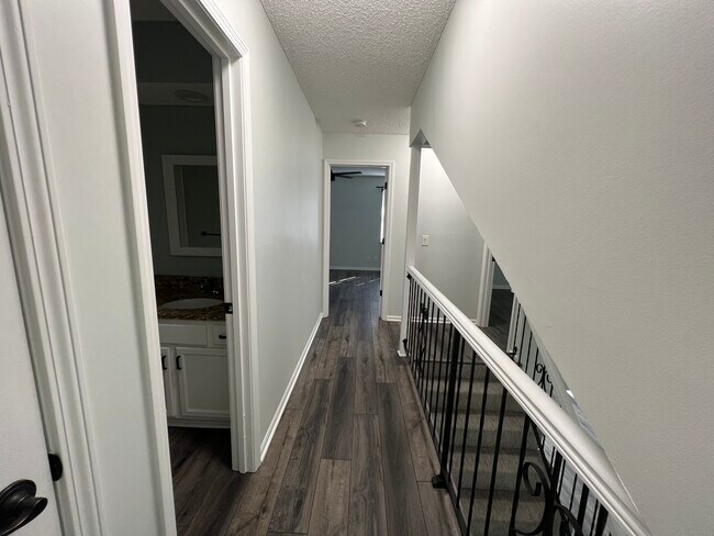 Upstairs hallway/2nd full bathroom/primary bedroom door/small bedroom door/top of stairs - 14103 W 88th Terrace