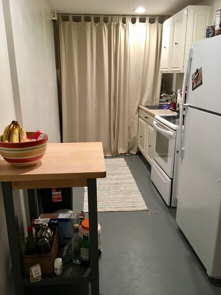 Galley Kitchen with movable island, in apartment washer and dryer (behind curtains), one year old fridge, and glass-top stove. - 3518 Northeast 94th Street