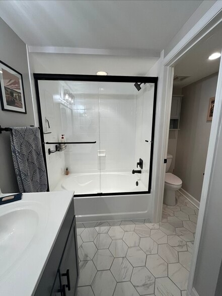 Completely updated bathroom including vanity with a modern mirror, new tile, and lighting. - 4079 S Four Mile Run Dr