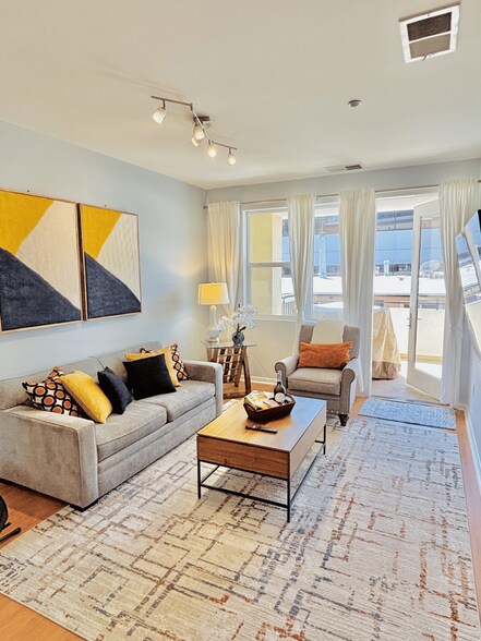 Bright, open living space with 65" 4K Smart TV, sleeper sofa & natural light. - 3687 4th Ave