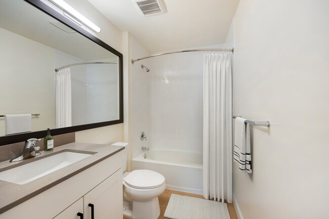 New Apartments bath with grey quartz countertop, white cabinetry, and hard surface flooring - Avalon Commons