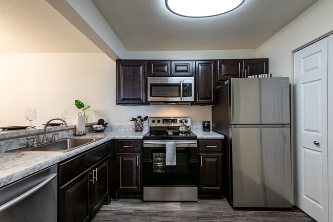 Fully equipped kitchen with stainless steel appliances and luxury vinyl flooring. - Shadowmoss Pointe Apartments and Townhomes