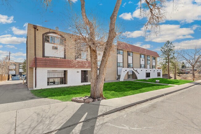 Charming apartment building with a classic red-tiled roof and well-maintained exterior, nestled in a serene neighborhood with lush green lawns and clear blue skies. - Country Club