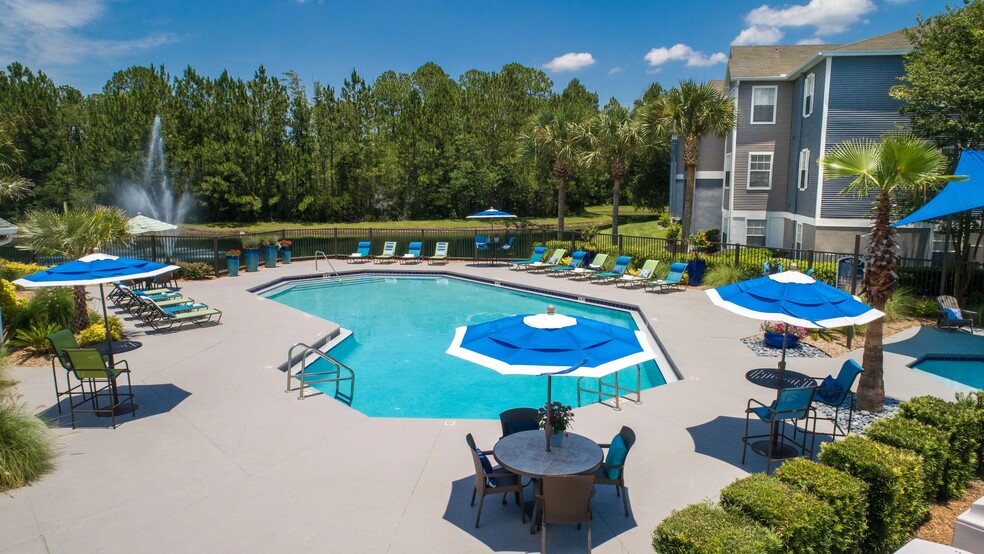 Dive into luxury from above! Our vibrant pool, sun loungers, and the tranquil lake fountain are a sight to behold. - Indigo Isles