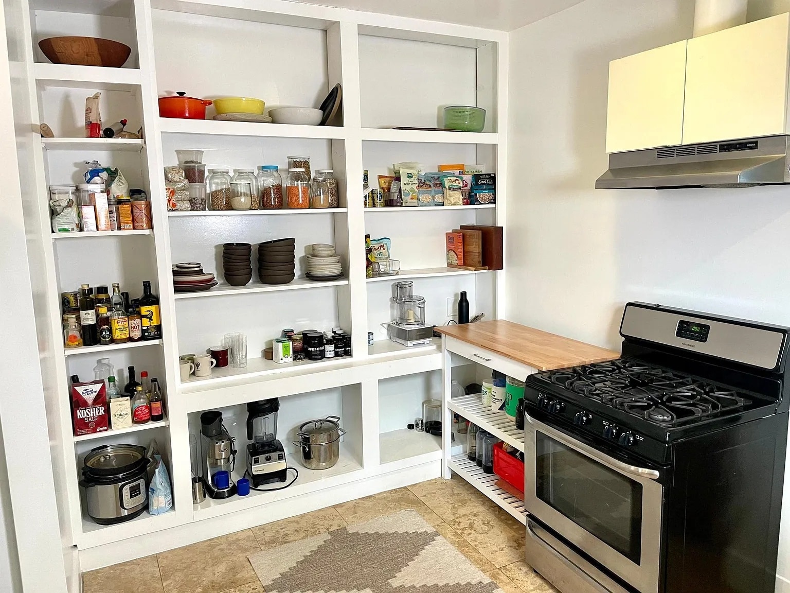 Functional kitchen with open shelving and a full-size gas range. - 6000 Carlton Way