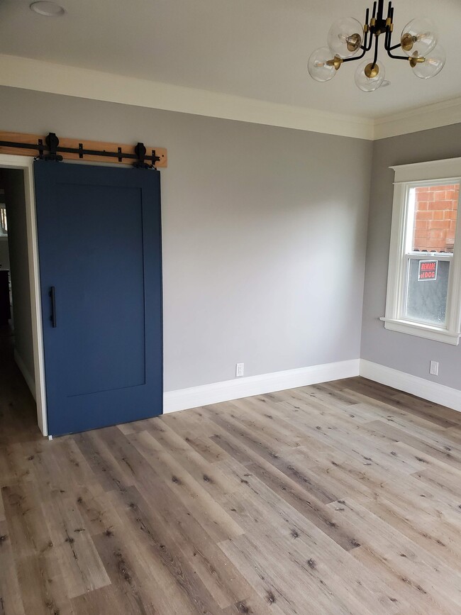 Living room with antique barn door original to property leading to hallway - 579 W. 13th St