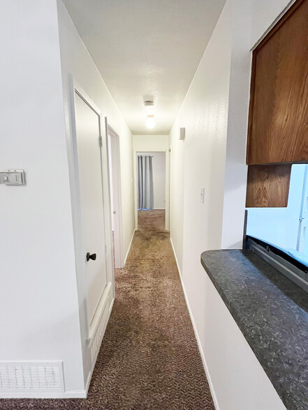 The hallway is a soft carpeted transitional space to bedrooms and bathroom with smoke alarm - 4917 Jamesway Rd