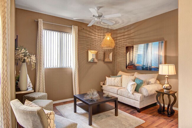 A living room with a ceiling fan and window overlooking the property - Pala Mesa